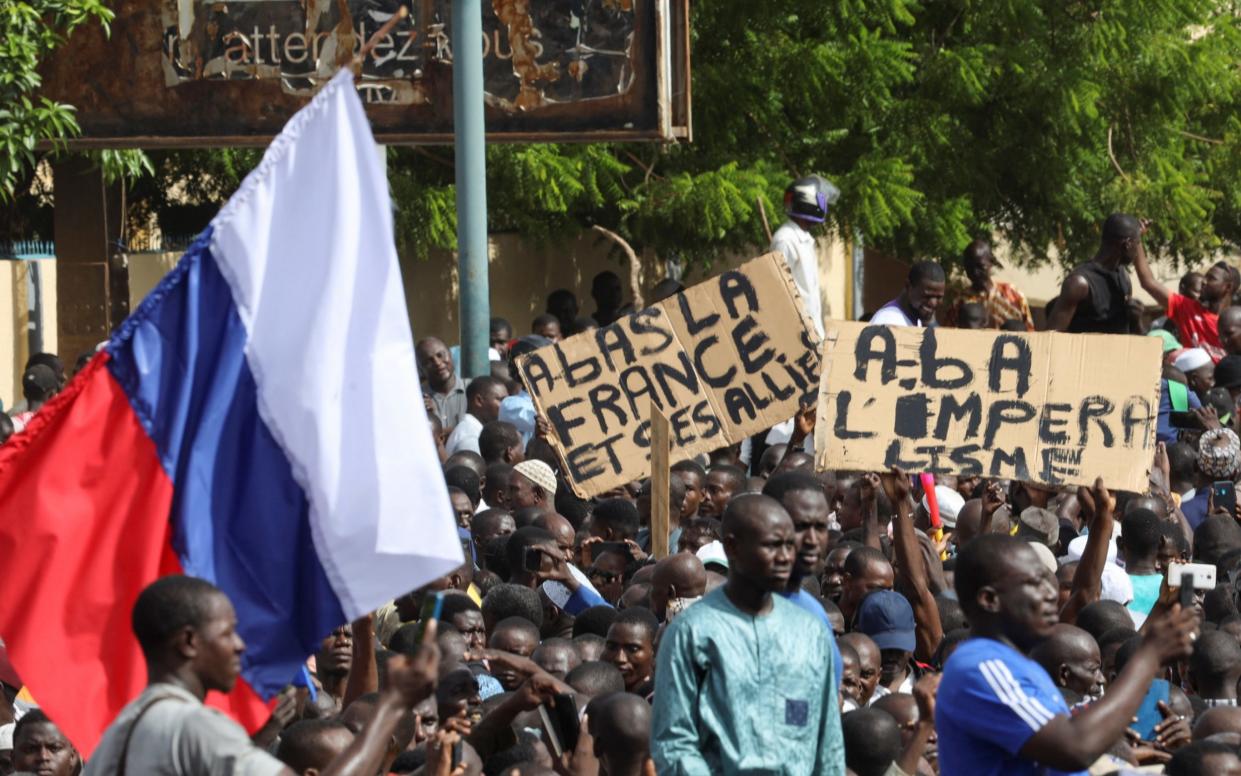 Demonstrators hold a Russian flag and banners during the gathering in support of the putschist soldiers in the capital Niamey