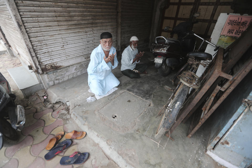 Indian Muslims offer Eid al-Adha prayers in front of a closed shop outside Jama Masjid in Ahmedabad, India, Saturday, Aug. 1, 2020. Eid al-Adha, or the Feast of the Sacrifice, is observed by sacrificing animals to commemorate the prophet Ibrahim's faith in being willing to sacrifice his son. (AP Photo/Ajit Solanki)