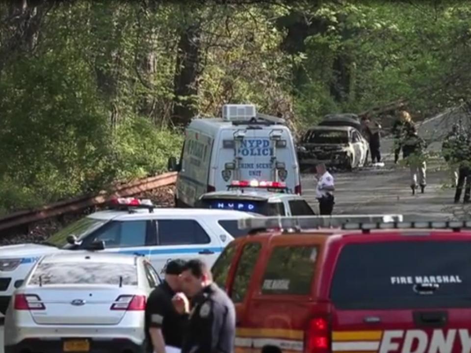 Police officers near the site in Bronx where the burnt car was found on Monday, 16 May 2022 (New York Post)