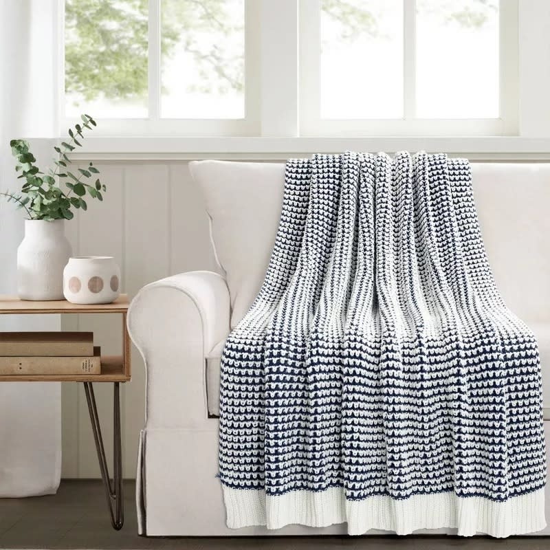 the knitted throw in navy and white over a couch