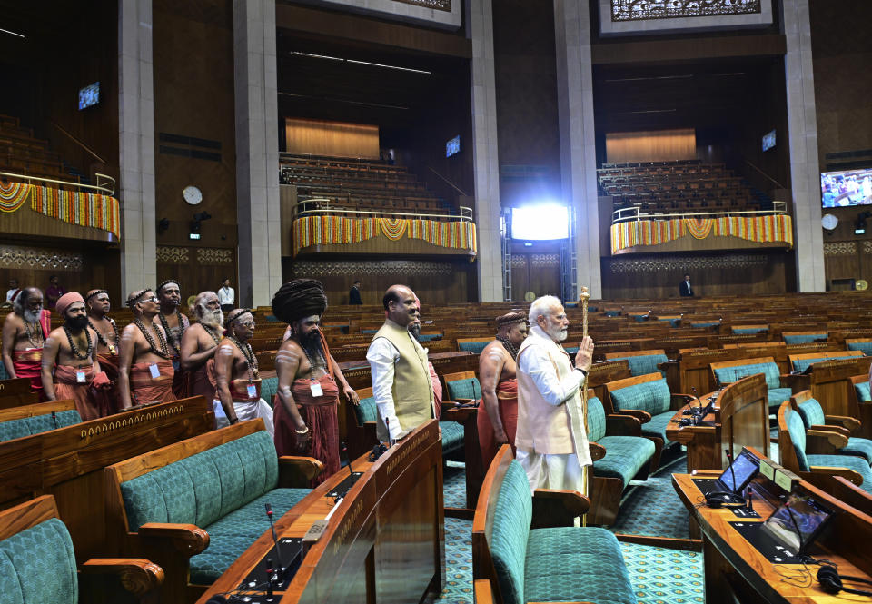 Indian prime minister Narendra Modi carries a royal golden sceptre to be installed it near the chair of the speaker during the start of the inaugural ceremony of the new parliament building, in New Delhi, India, Sunday, May 28, 2023. The new triangular parliament building, built at an estimated cost of $120 million, is part of a $2.8 billion revamp of British-era offices and residences in central New Delhi called "Central Vista", even as India's major opposition parties boycotted the inauguration, in a rare show of unity against the Hindu nationalist ruling party that has completed nine years in power and is seeking a third term in crucial general elections next year. (AP Photo)