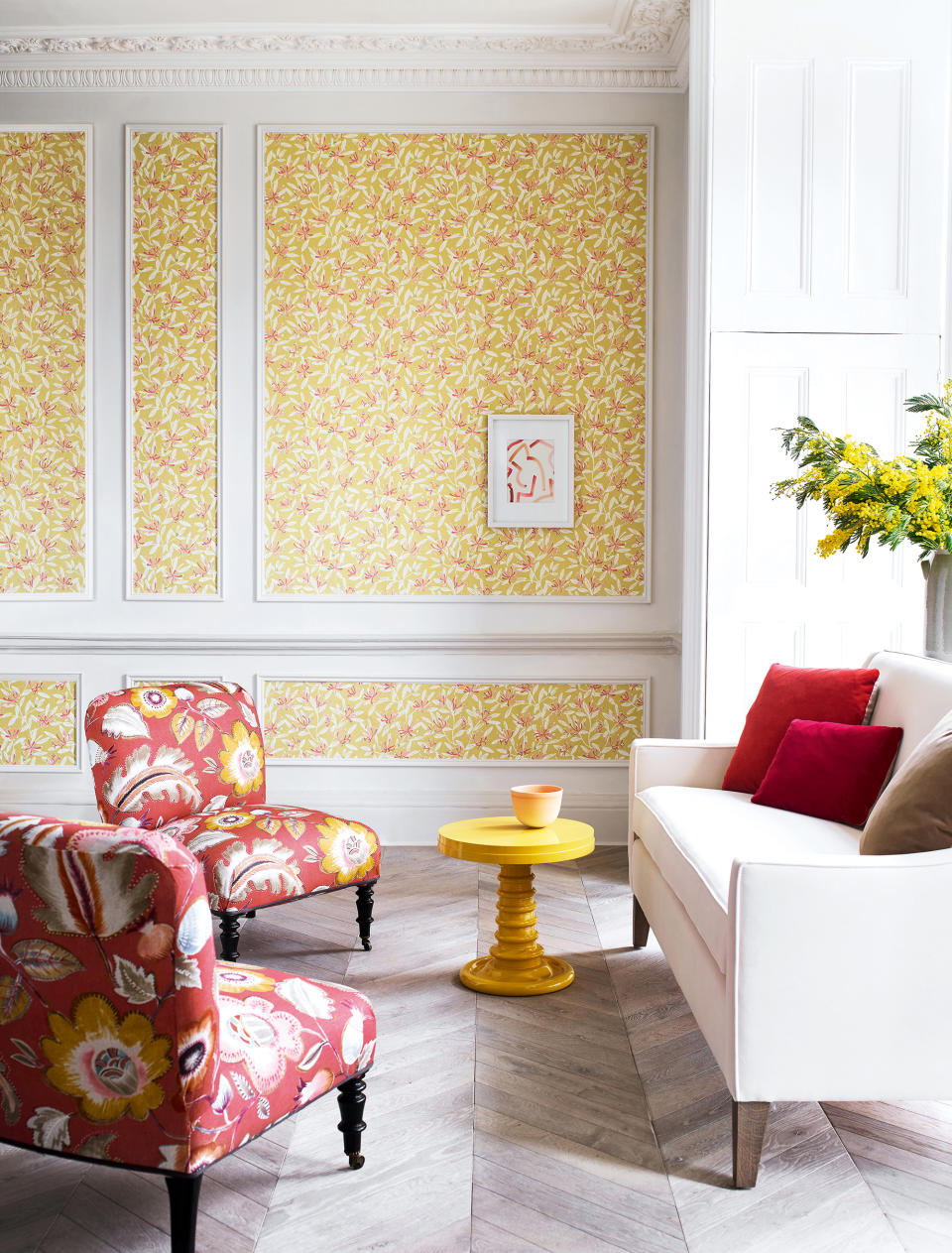 <p> A living room wallpaper is a fabulous way to bring color into a space. A mural or a large-scale design can make a  bold statement but is not for everyone. For something that's easy to live with choose a small-scale repeat design such as the joyful Honeysuckle design from Jane Churchill in this yellow living room idea. </p> <p> Setting it within wall paneling will also help calm the look. While this paper appears sunshine yellow at first glance, it does in fact have an array of colors within it including pink and red which have here been drawn out as accent colors and used on the upholstery to create a playful contrast. </p>