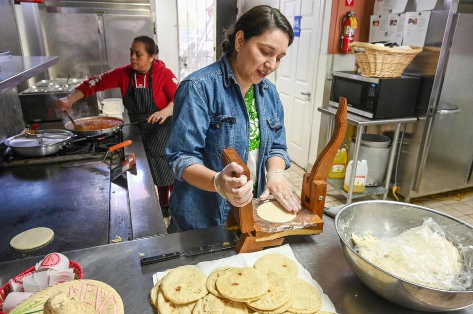 Lizett López usa una prensa de tortillas para hacer gorditas caseras, que son más gruesas que las tortillas normales, mientras María Verdín cocina picadillo rojo con papas, uno de los varios rellenos disponibles para las gorditas, en la estufa de Lucy's Gorditas, en Fresno, el miércoles 19 de abril de 2023.