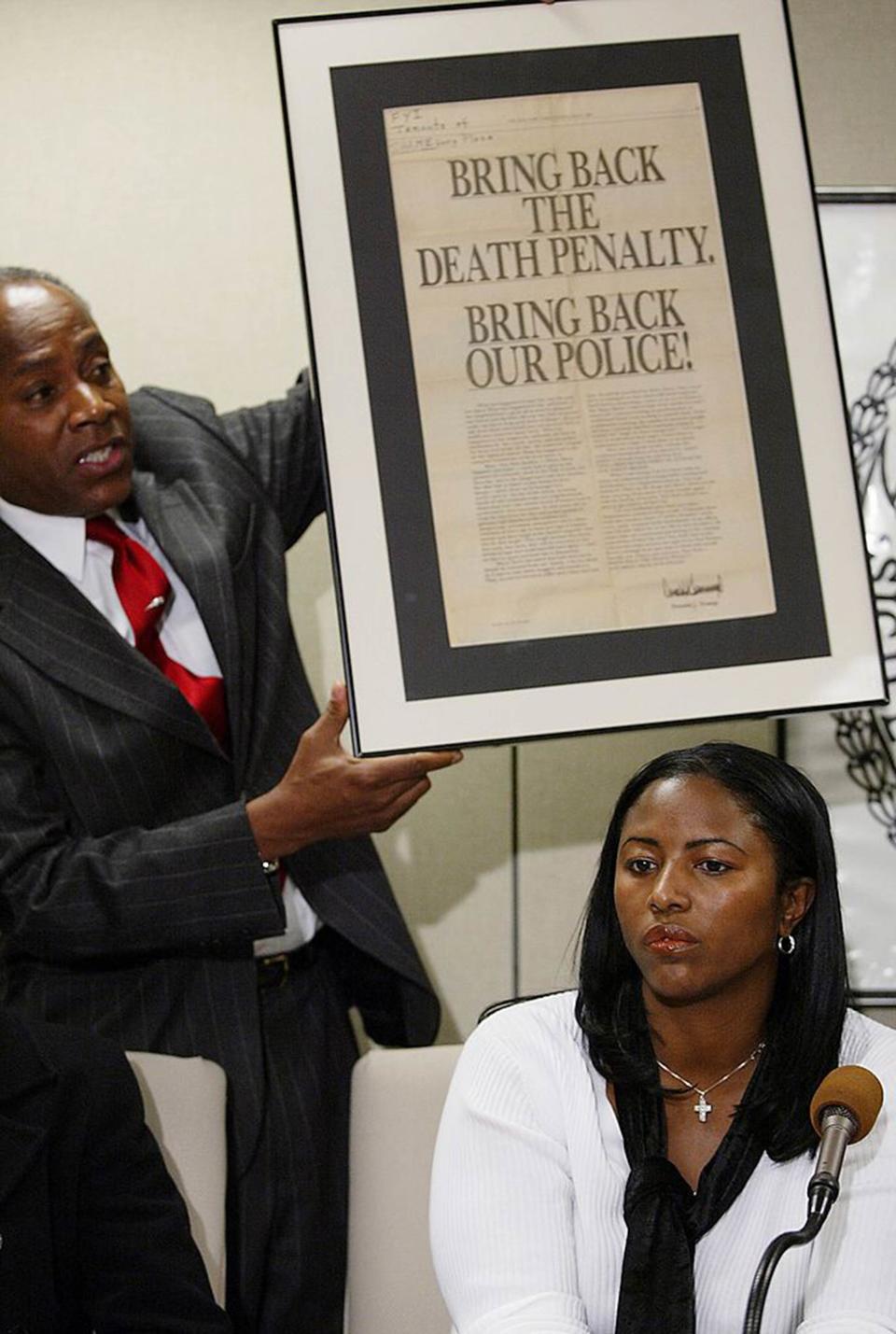 Harlem, N.Y. City Councilman Bill Perkins holds up a May 1, 1989, ad taken out by Donald Trump in the days after the crime. Seated, Angela Cuffie meets reporters at Manhattan Supreme Court where a judge overturned the conviction of her brother, Kevin Richardson, and four other men who had been jailed in the Central Park jogger case on Dec. 19, 2002. | Mike Albans/NY Daily News Archive—Getty Images