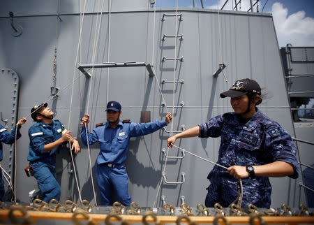 A female navigator of Japanese helicopter carrier Kaga (R) prepares to practice raising sign signal flags in the Indian Ocean, Indonesia, September 23, 2018. The proportion of women in the Kaga's 450-strong crew is about 9 percent, a level Japan is targeting for the military overall by 2030 from 6 percent now. That would still fall short of U.S., where 15 percent of people in uniform are women, and Britain with 10 percent. REUTERS/Kim Kyung-Hoon