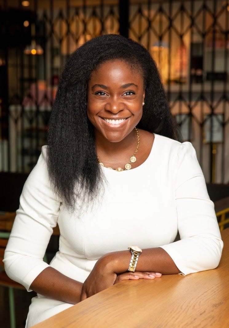 Janice Omadeke sits smiling in a white dress