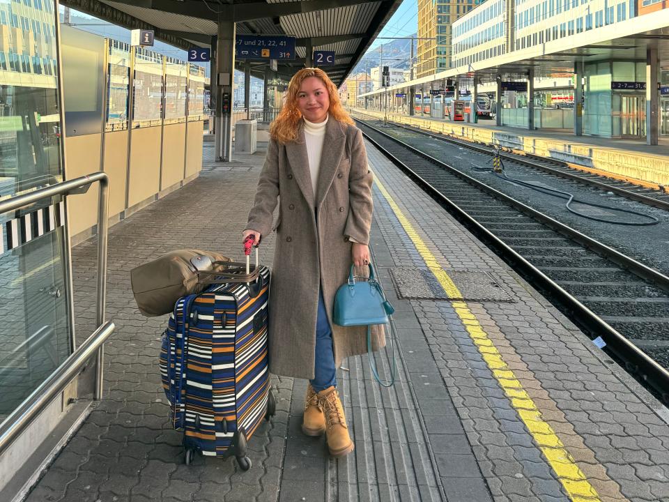 woman with large suitcase on train track