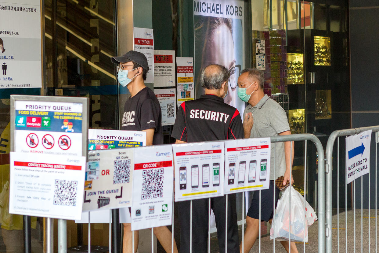 People in face masks seen walking by a security guard at the entrance to Clementi Mall on 12 May 2020. (PHOTO: Dhany Osman / Yahoo News Singapore)