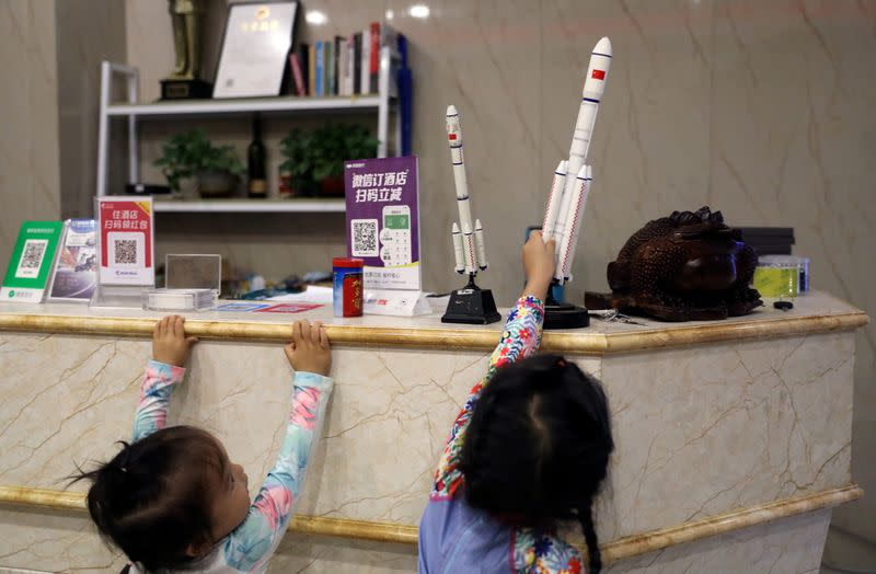 Children play with models of rockets at the reception desk of a hotel in Longlou town, Wenchang