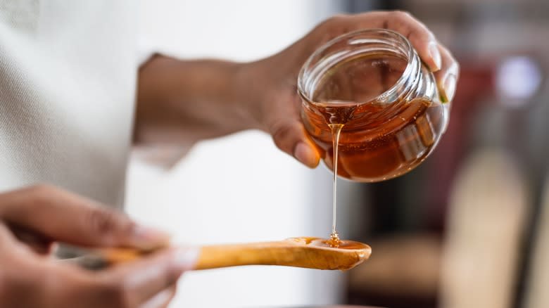 man pours honey on spoon