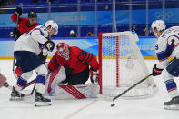 Canada goalkeeper Eddie Pasquale (80) watches as United States' Ben Meyers (39) and Noah Cates (27) close in during a preliminary round men's hockey game at the 2022 Winter Olympics, Saturday, Feb. 12, 2022, in Beijing. (AP Photo/Matt Slocum)