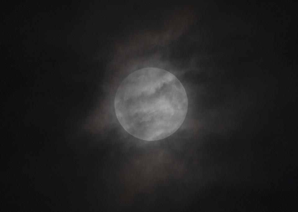 A penumbral lunar eclipse is seen through cloud during the early hours of Saturday, May 6, 2023 in Beijing. (AP Photo/Ng Han Guan)