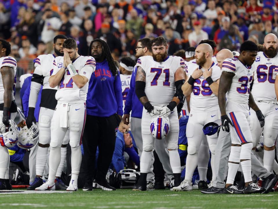 Buffalo Bills players surround a medical team tending to Damar Hamlin after his cardiac arrest on the football field.