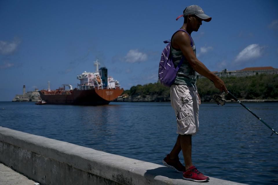A fisherman walks on the Malecon seawall where an oil tanker can be see in the background in Havana, Cuba, Wednesday, April 17, 2019. Washington has sanctioned Venezuela’s oil industry and shipping companies that move Venezuelan oil to Cuba. (AP Photo/Ramon Espinosa)