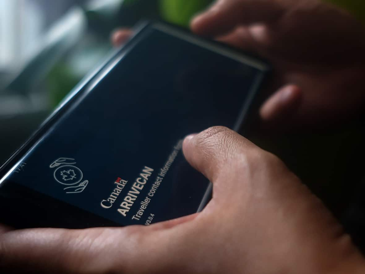 A person holds a smartphone set to the opening screen of the ArriveCan app in Toronto on June 29, 2022. (Giordano Ciampini/The Canadian Press - image credit)