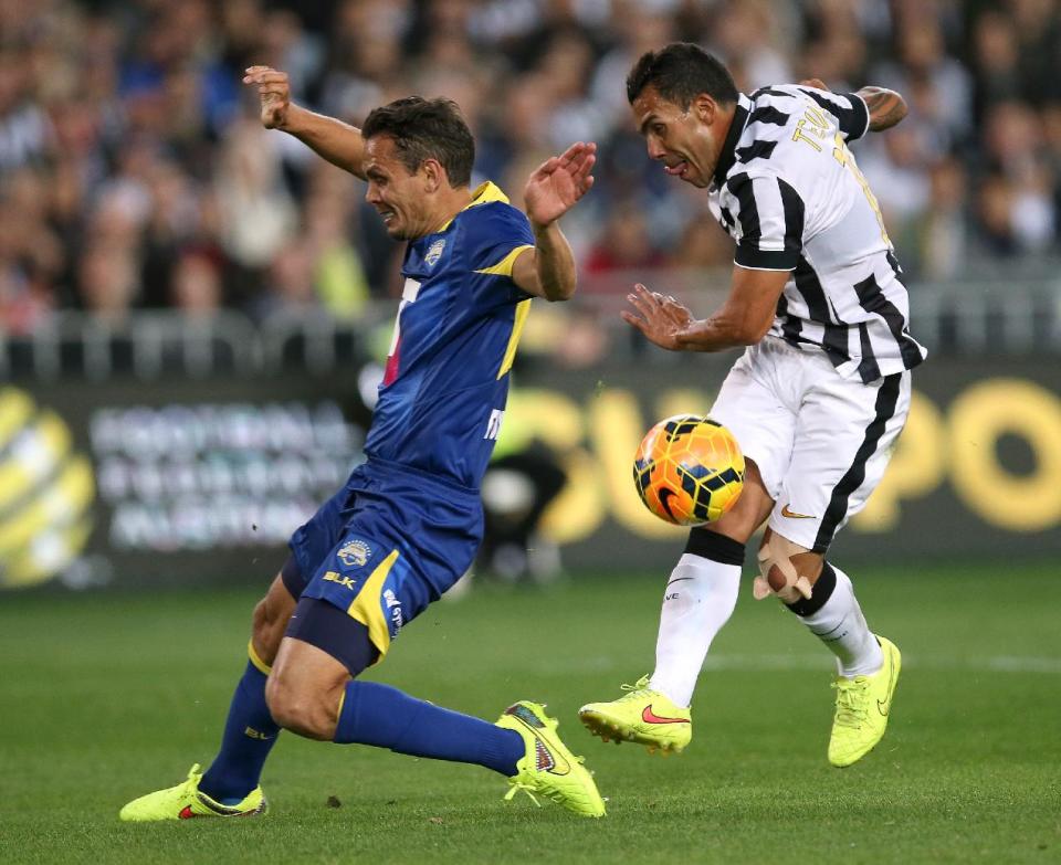 Juventus&#39; Carlos Tevez, right, attempts to shot past Australian A-League&#39;s Jade North during their exhibition soccer match in Sydney, Sunday, Aug. 10, 2014. (AP Photo/Rick Rycroft)