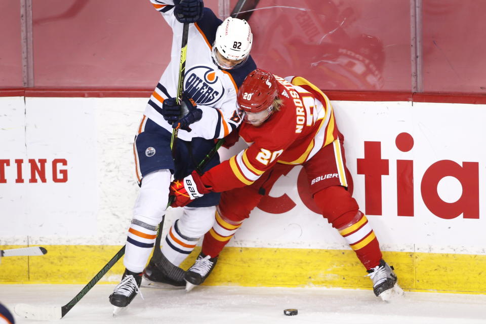 Edmonton Oilers' Caleb Jones, left, works for the puck against Calgary Flames' Joakim Nordstrom during the second period of an NHL hockey game Saturday, April 10, 2021, in Calgary, Alberta. (Larry MacDougal/The Canadian Press via AP)