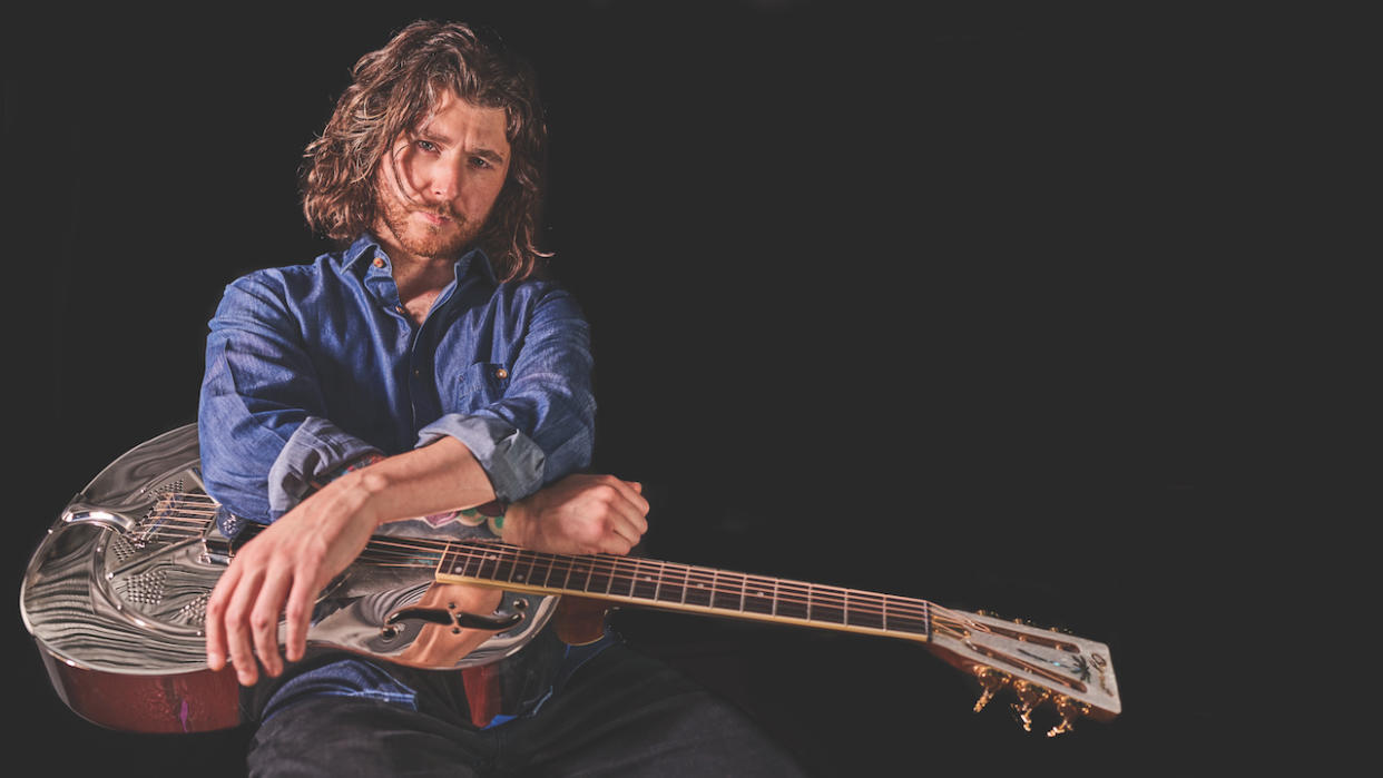  Colour portrait of blues guitarist Dom Martin seated with an Ozark Resonator guitar . 