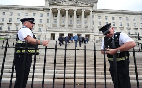 A security guard locks the gates outside Parliament Buildings at Stormont in Belfast - Credit: PA