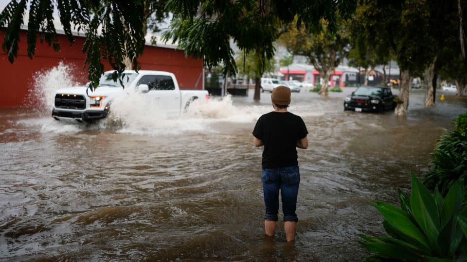 A man watches motorists drive through a flooded street during a rain storm Thursday in Santa Barbara, California. - Jae C. Hong/AP