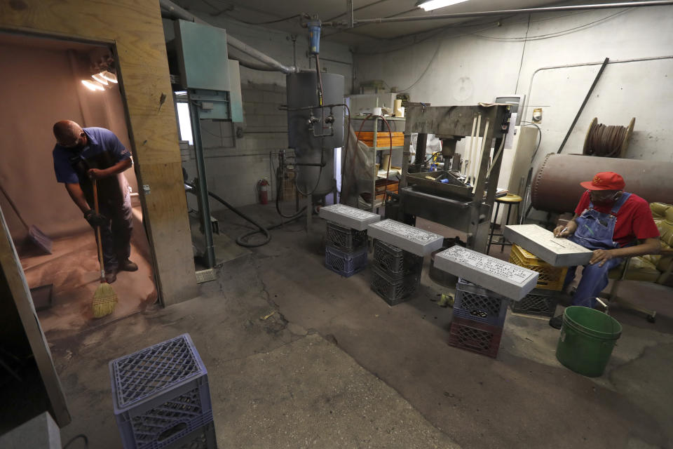 Leon Brown, left, sweeps up and recycles sand Thursday, May 28, 2020, as Hosea Knox prepares the next tombstone for sandblasting in Knox's shop on Chicago's Southside. (AP Photo/Charles Rex Arbogast)