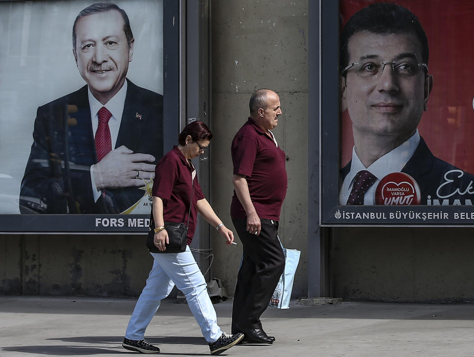 FILE- In this Tuesday, June 4, 2019 file photo, people walk past posters of Turkey's President Recep Tayyip Erdogan, left, and Ekrem Imamoglu, right, Istanbul's mayoral candidate of the secular opposition Republican People's Party, or CHP, ahead of June 23 re-run of Istanbul elections, in Istanbul. Millions of voters in Istanbul go back to the polls for a controversial mayoral election re-run Sunday, as President Recep Tayyip Erdogan's party tries to wrest back control of Turkey's largest city. (AP Photo/Emrah Gurel, File)