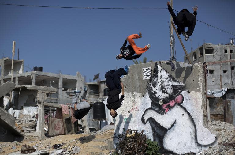 Palestinian youths practice their Parkour skills near a mural said to have been painted by British street artist Banksy