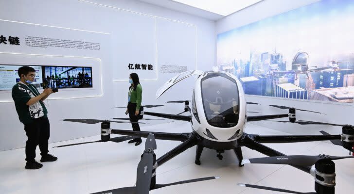 An image of a lifesize white and black pilotable drone display in China with a man taking a picture of a woman in front of it.