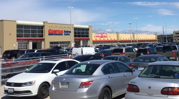 The exterior of a Costco, as seen from across a crowded parking lot.