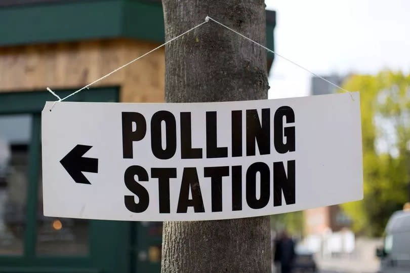 Polling station sign hanging on a tree.