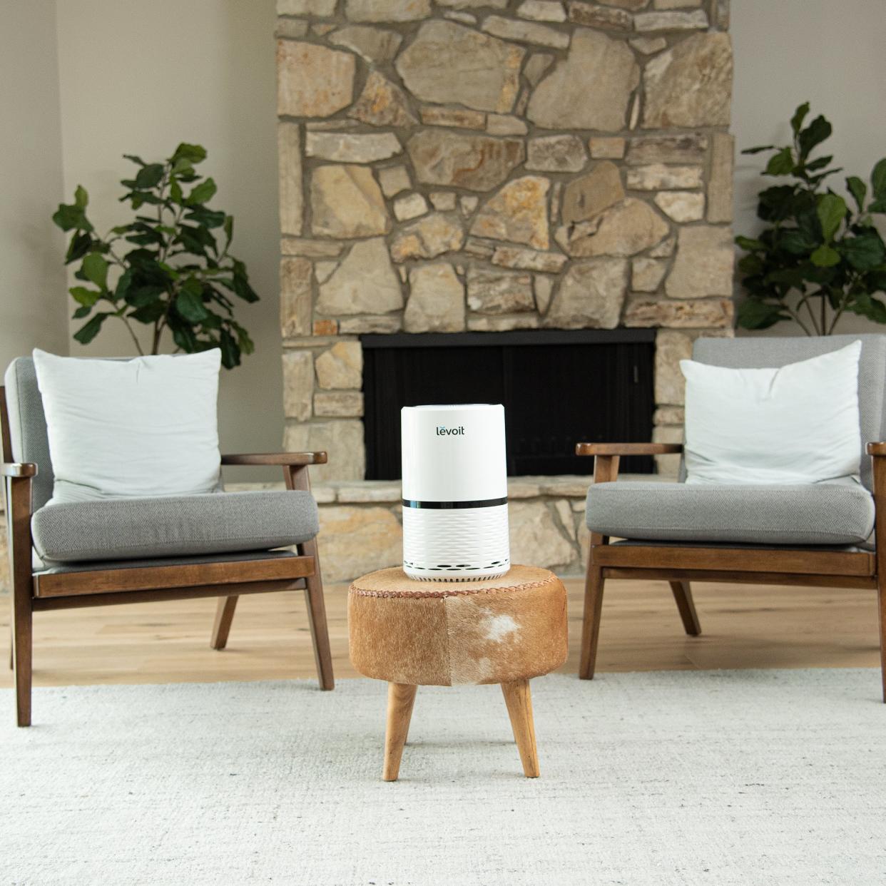 Levoit Air Purifier on a side table between two chairs. 