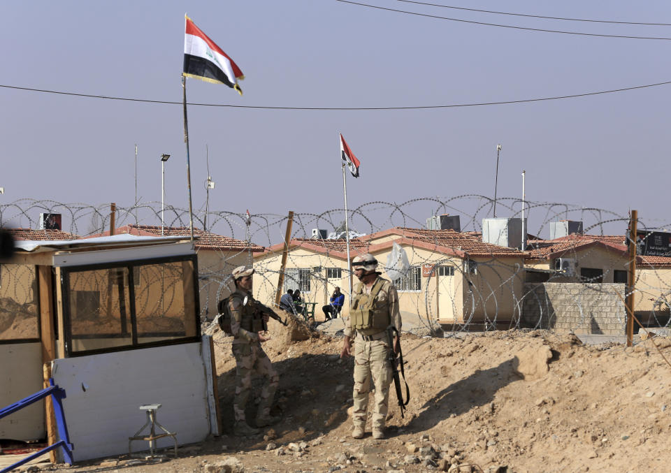 In this Tuesday, Nov. 13, 2018 photo, Iraqi soldiers stand guard with their weapons on the border crossing with Syria, in Qaim, Anbar province, Iraq. More than a year after this Iraqi town was freed from the Islamic State group, booms from airstrikes still echo and columns of smoke are visible, rising beyond the earthen berms and concrete walls marking the border with Syria. On the other side, the fight is raging to capture one of the militant group’s last enclaves. (AP Photo/Hadi Mizban)
