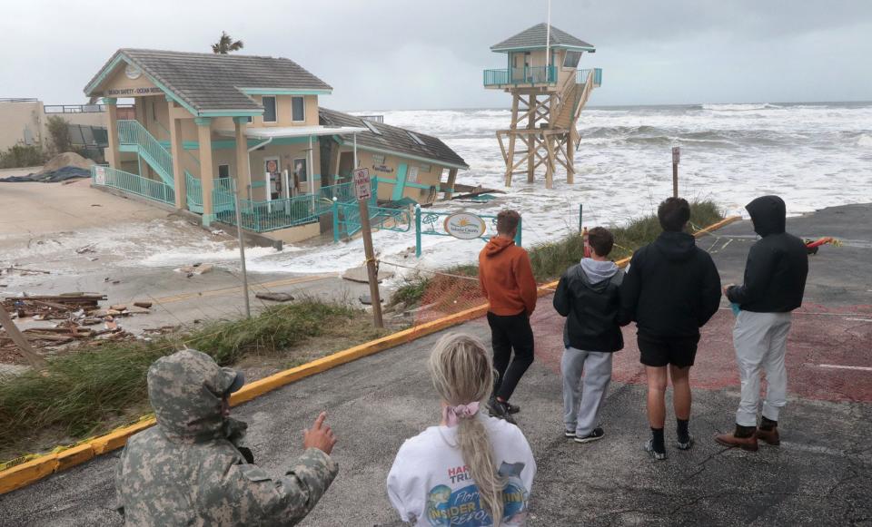 Storm watchers checkout the damage to the Volusia County Beach Safety office at the Dunlawton beach ramp on Wednesday as Tropical Storm Nicole moves closer to Volusia and Flagler counties.