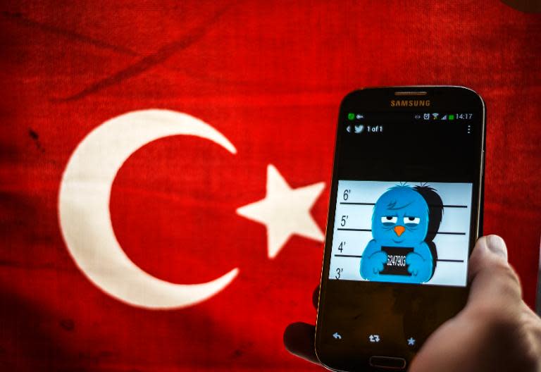 Picture taken in Istanbul on March 26, 2014, shows a mugshot of the Twitter bird on a smartphone with the Turkish flag in the background