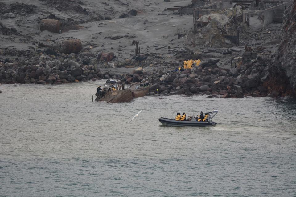 A boat passes ash-covered White Island after the volcano erupted.