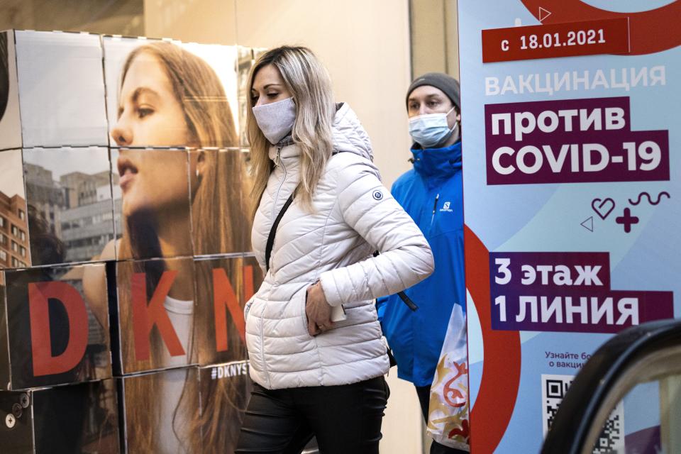 A woman wearing a face mask to protect against coronavirus walks past a poster reading "vaccination against COVID-19" at the GUM, the State Department store, near Red Square in Moscow, Russia, Wednesday, March 31, 2021. Russia has boasted about being the first country in the world to authorize a coronavirus vaccine and rushed to roll it out earlier than other countries, even as large-scale testing necessary to ensure its safety and effectiveness was still ongoing. (AP Photo/Alexander Zemlianichenko)