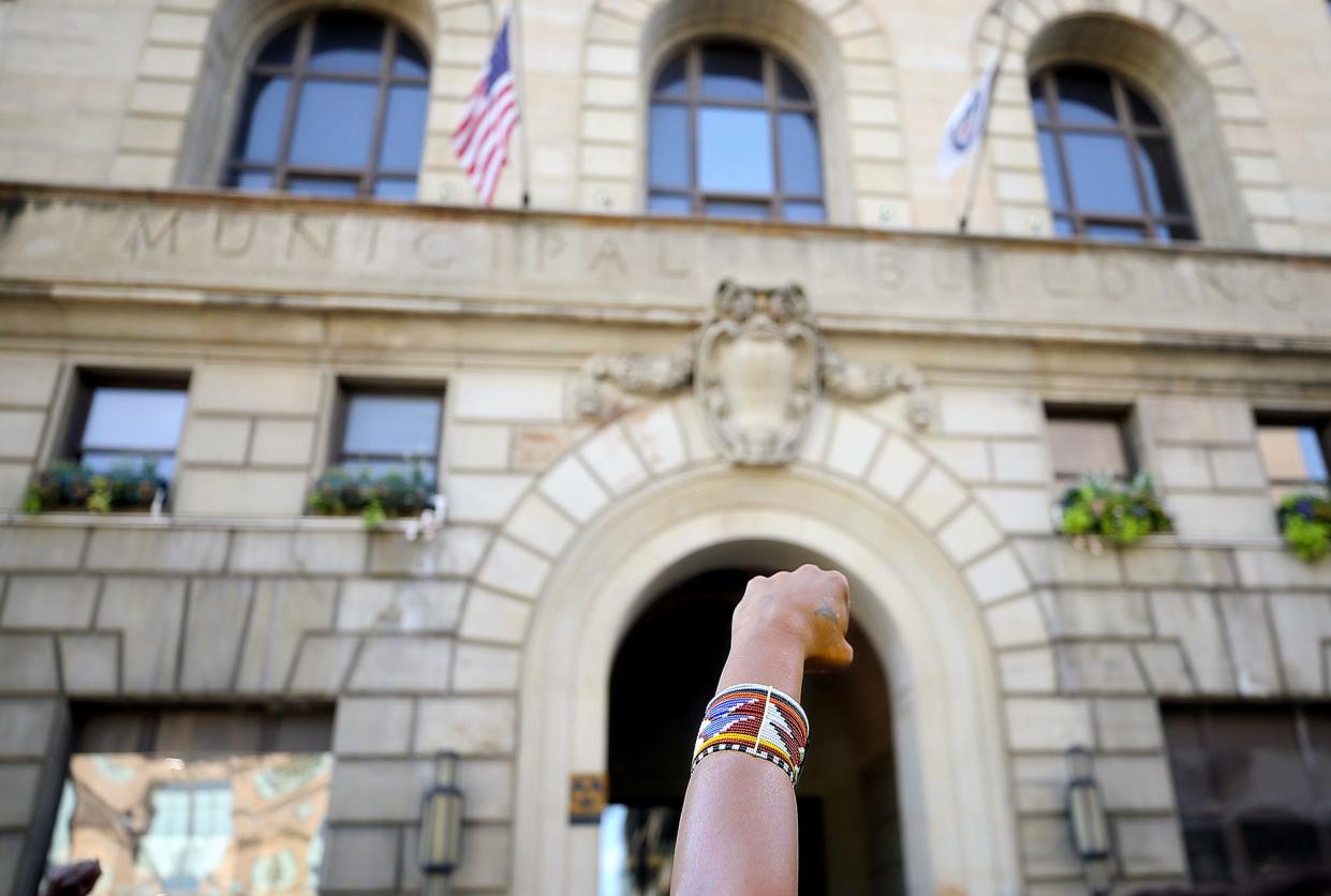 An activist raises a fist Monday as speakers discuss the police shooting death of Jayland Walker during a rally outside Akron City Hall.