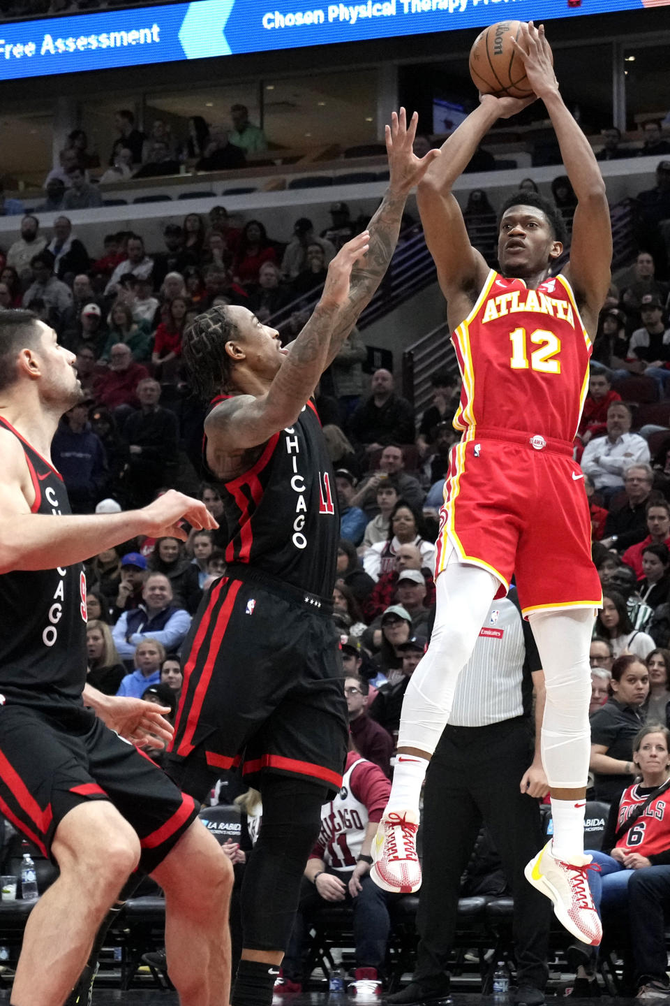 Atlanta Hawks forward De'Andre Hunter, right, shoots over Chicago Bulls center Nikola Vucevic, left, and forward DeMar DeRozan during the first half of an NBA basketball game in Chicago, Monday, April 1, 2024. (AP Photo/Nam Y. Huh)
