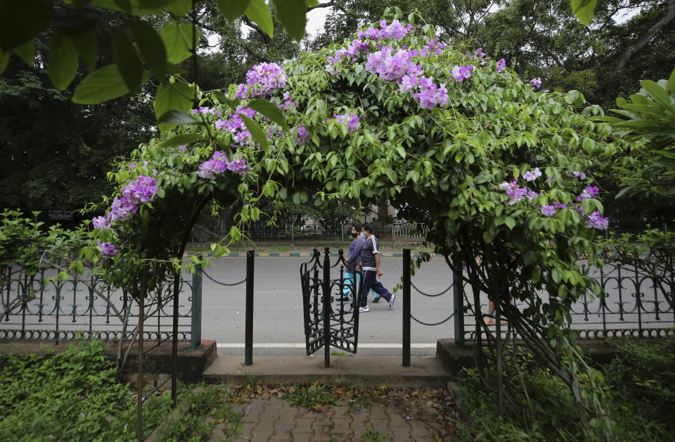 An Indian couple wearing face masks as a precaution against the coronavirus walk outside a public park in Bengaluru, India, Wednesday, June 16, 2021. Public parks and other open spaces in the city were thrown open to public since Monday after partially easing restrictions following a drop in new infections. Authorities are still warning people to wear face masks and maintain a safe distance. (AP Photo/Aijaz Rahi)