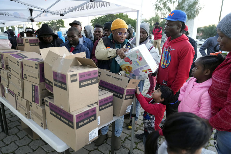 Migrants receive toys at an entry point, Tuesday, Dec. 20, 2022, in Tijuana, Mexico. The U.S. government made its plea in a filing a day after Chief Justice John Roberts issued a temporary order to keep the pandemic-era limits on migrants in place. (AP Photo/Marcio Jose Sanchez)