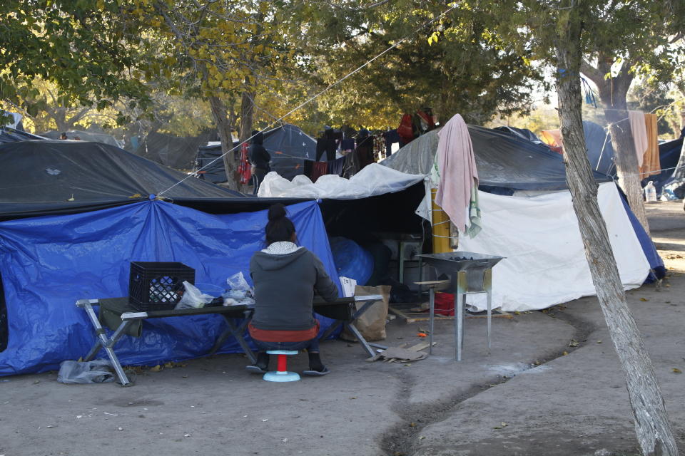 In this Tuesday, Dec. 3, 2019 photo, a woman from Michoacan, in southern Mexico, prepares a dinner of eggs and beef using a wood-fuel grill outsider her tent in a 250-person encampment in a public park in Juarez, Mexico, a quarter of a mile away from a border crossing to El Paso, Texas. Residents of the camp said that they are fleeing violence and gang impunity in southern Mexico. Those at the front of the line say they've been in the camp for 10 weeks. (AP Photo/Cedar Attanasio)