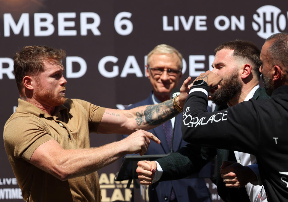 Canelo Alvarez (pictured left) brawls with Caleb Plant (pictured right) during a face-off.