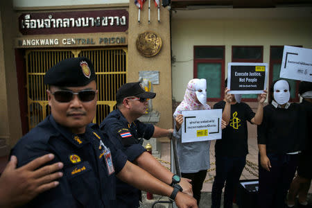 Prison wardens stand guard as demonstrators from Amnesty International hold placards outside the Bang Kwang Central Prison to protest against the death penalty in Bangkok, Thailand, June 19, 2018. REUTERS/Athit Perawongmetha