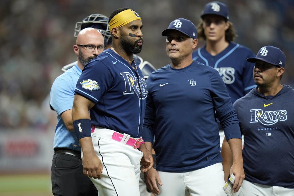 Tampa Bay Rays first baseman Yandy Diaz, second from left, is checked on by manager Kevin Cash after getting injured fielding a ground out by Miami Marlins' Jacob Stallings during the third inning of a baseball game Tuesday, July 25, 2023, in St. Petersburg, Fla. Diaz left the game. (AP Photo/Chris O'Meara)