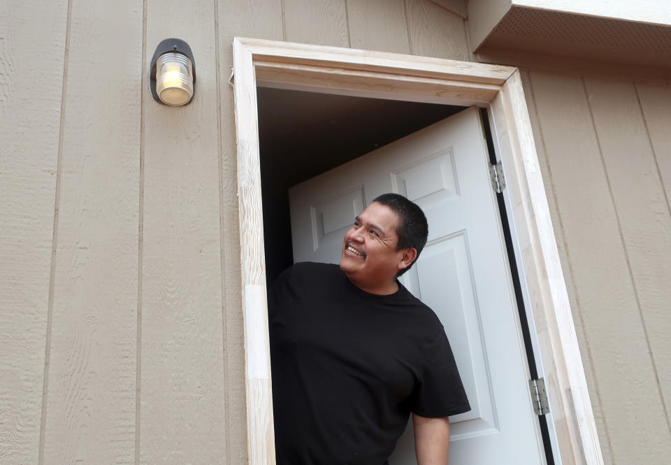 In this Thursday, May 9, 2019 photo Jimmie Long Jr. smiles after a utility crew hooks up power to his home in Kaibeto, Arizona, on the Navajo Nation. An ambitious project to connect homes to the electric grid on the country's largest American Indian reservation is wrapping up. Utility crews from across the U.S. have volunteered their time over the past few weeks to hook up about 300 homes on the Navajo Nation. (AP Photo/Felicia Fonseca)