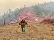 A firefighter walks along a hillside covered with flame retardant during the Elkhorn Fire near Red Bluff