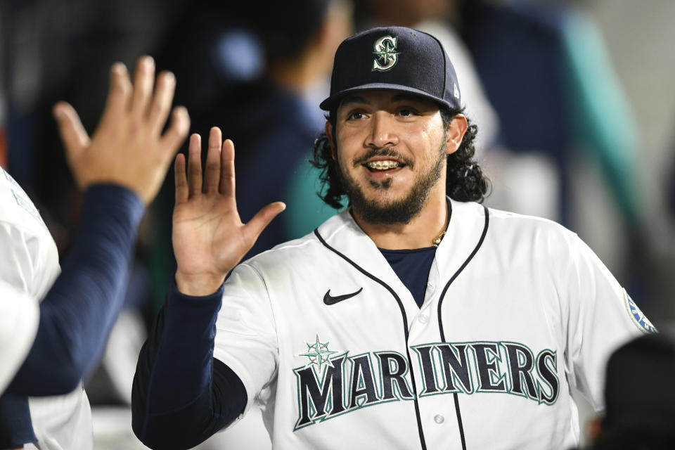 Seattle Mariners relief pitcher Andres Munoz high-fives his teammates in the dugout after striking out two Texas Rangers during the eighth inning of a baseball game Wednesday, Sept. 28, 2022, in Seattle. (AP Photo/Caean Couto)