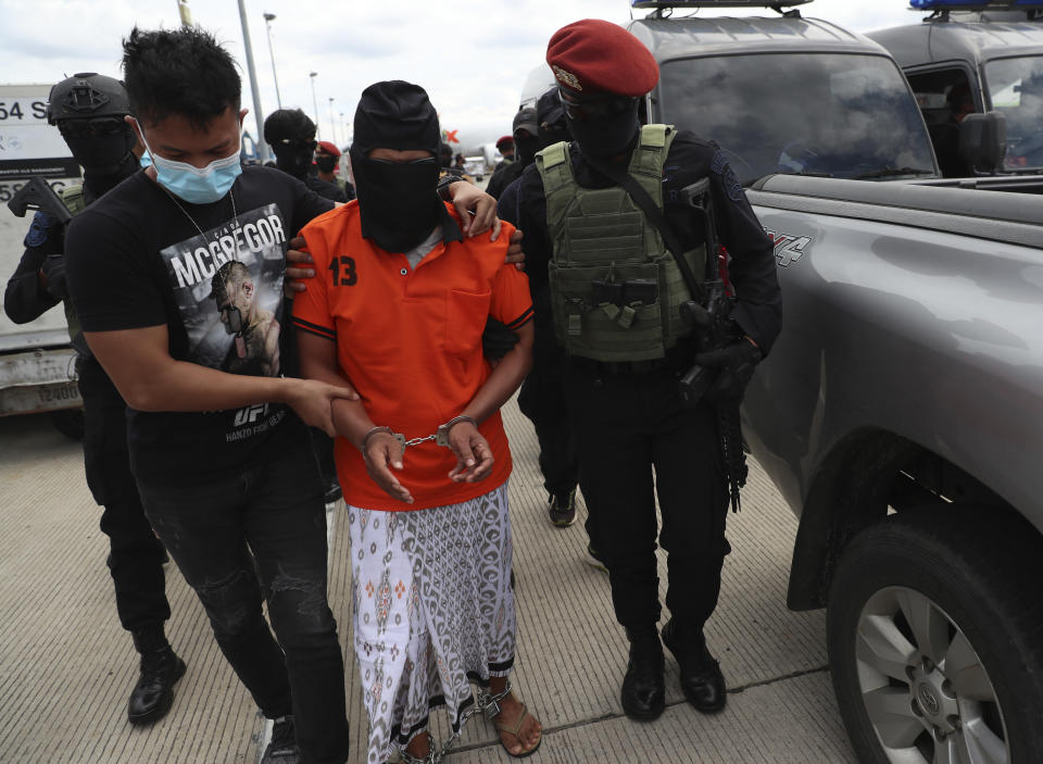 Police officers escort suspected militant Zulkarnaen, center, who is also known as Aris Sumarsono, upon arrival at Soekarno-Hatta International Airport in Tangerang, Indonesia, Wednesday, Dec. 16, 2020. Indonesian authorities have transferred suspected militants arrested in recent weeks to the country’s capital, including Zulkarnaen, a bomb maker and the architect of a series of deadly attacks and sectarian conflicts in the world’s largest Muslim majority nation. (AP Photo/Achmad Ibrahim)