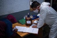 Un hombre firma en un registro antes de recibir la urna que contiene los restos de su padre, una víctima del COVID-19 que ha sido cremada en este lugar. (Photo by PEDRO PARDO/AFP via Getty Images)