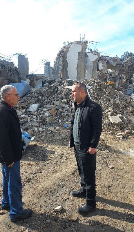 Hezbollah lawmaker Hassan Fadlallah stands near rubble of a destroyed building in Aita al-Shaab
